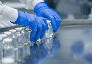 Hands arranging vials in a laboratory setting.